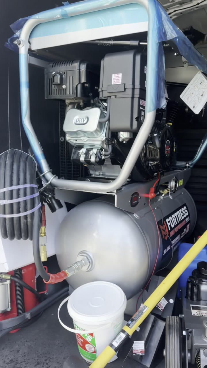 Gas compressor and coiled air hose mounted in the van, ready to inflate a tire on the roadside
