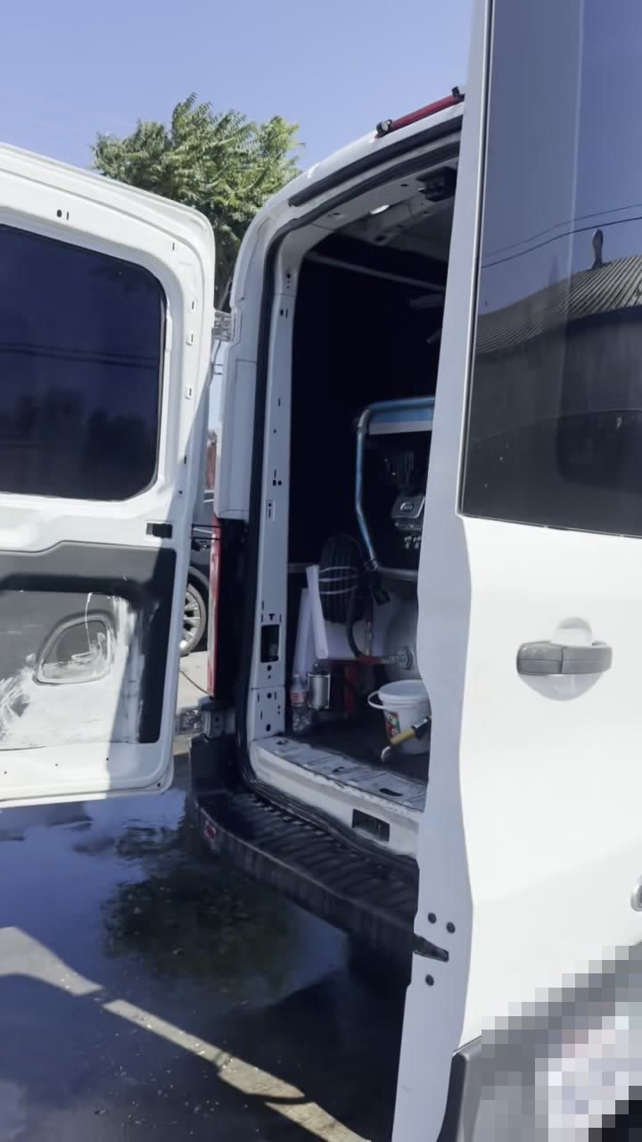 The service van with its rear doors open in a yard, ready to unload